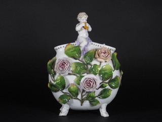 A Continental porcelain vase with floral encrusted decoration surmounted by a figure of a cherub 10"