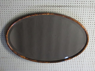An oval bevelled plate wall mirror contained in a tortoiseshell  effect frame 30"w x 20"h