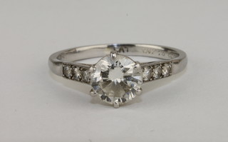 A lady's platinum engagement/dress ring set a circular cut diamond and with small diamonds to the shoulders