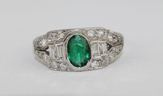 A lady's 18ct white gold dress ring set an oval cut emerald  surrounded by diamonds, approx 0.75/0.55ct