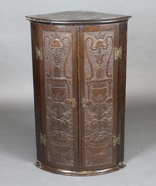 A 19th Century carved oak hanging corner cabinet with shelved interior enclosed by panelled doors 23"w x 37"h x 16"d
