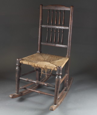An 18th Century elm spindle back rocking chair with woven rush seat