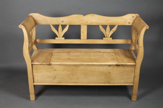 A pine settle with pierced back, the base fitted a hinged lid raised  on square supports 51"w x 16"d x 35"h