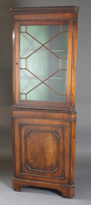 A mahogany double corner cabinet the upper section with  moulded and dentil cornice, the shelved interior enclosed by  astragal glazed panelled door, the base fitted a cupboard enclosed  by panelled doors, raised on bracket feet 27"w x 15"d x 75"h