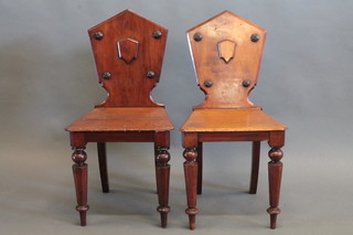 A pair of 19th Century mahogany hall chairs, raised on turned supports
