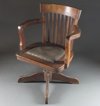 An Edwardian oak stick and rail back revolving office chair