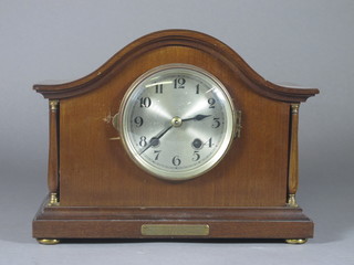 A striking mantel clock with silvered dial and Arabic numerals contained in a mahogany arched case