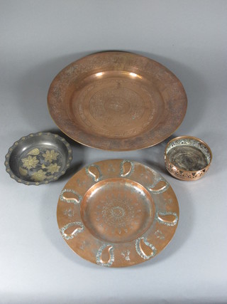 An Eastern circular embossed copper charger 16 1/2", do. dish  11", an Oriental metal dish 7" and a copper wine bottle coaster
