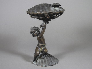 A bronze trinket box in the form of a clam shell supported by a  figure of a cherub 8"