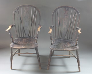 A pair of elm stick and wheel back carver chairs with solid seats  and H framed stretcher, raised on turned supports