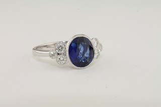 A lady's 18ct white gold dress ring set an oval sapphire supported  by diamonds and with 3 diamonds to each shoulder