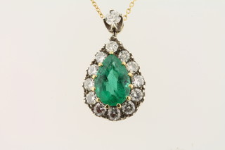 A lady's tear drop shaped emerald pendant surrounded by  diamonds hung on a fine gold chain