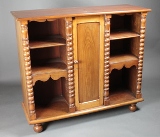 A 19th Century mahogany bookcase, the centre fitted a cupboard flanked by shelves with spiral turned columns to the sides, raised  on bun feet 48"w x 17 1/2"d x 43"h