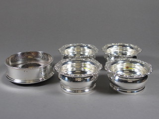 A circular silver plated bottle coaster and 4 others
