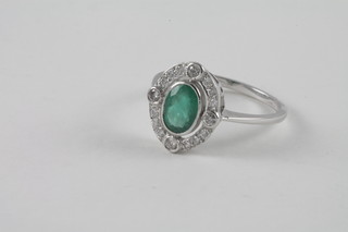 A lady's 18ct white gold dress ring set an oval emerald  surrounded by diamonds