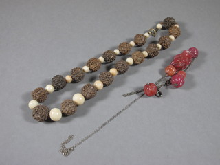 An Oriental carved wooden necklace together with an Oriental  carved red glass necklace