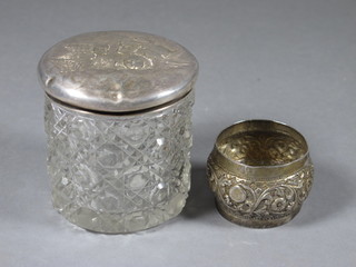 A circular hobnail cut glass dressing table jar with embossed  silver lid decorated angels and an Eastern embossed white metal  napkin ring