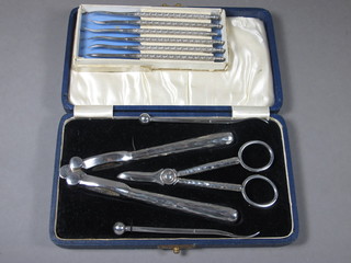 A pair of silver plated nut crackers, a pair of silver plated grape scissors and nut picks, cased together with 6 nut picks