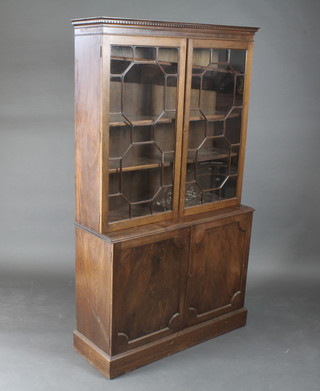 A 19th Century mahogany bookcase on cabinet with moulded and  dentil cornice, the upper section fitted adjustable shelves enclosed  by astragal glazed panelled doors, the base fitted a cupboard  enclosed by panelled doors, raised on a platform base 43"w x  14"d x 72"h