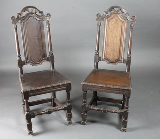A pair of 18th Century oak high back hall chairs with solid seats, raised on turned and block supports