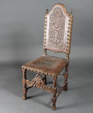 A Continental 17th Century style oak and leather high back hall chair with embossed back and carved stretcher, raised on turned  supports  ILLUSTRATED