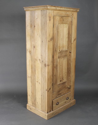 A Continental pine wardrobe enclosed by a panelled door, the  base fitted a drawer, raised on a platform base 33"w x 22"d x  73"h