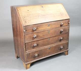 A Georgian oak bureau the fall front revealing a well fitted  interior above 4 long drawers with tore handles, raised on bracket  feet 39"w x 20"d x 42"h