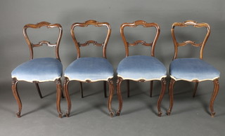 A set of 4 Victorian mahogany balloon back dining chairs with shaped mid rails, seats upholstered in blue material, raised on  carved French cabriole supports