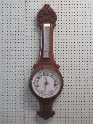 An aneroid barometer and thermometer with enamelled dial contained in a carved honey oak case