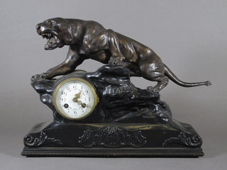 A 19th Century French 8 day striking mantel clock with  enamelled dial and Arabic numerals contained in a spelter case  surmounted by a figure of a tiger  ILLUSTRATED