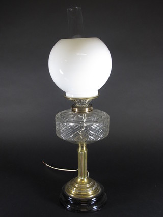 A Victorian glass and brass oil lamp raised on a brass column  complete with chimney and shade, converted to an electric table  lamp