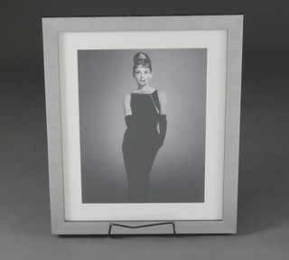 A print of Audrey Hepburn in the Breakfast at Tiffany's style, posting in a black dress with long cigarette holder, contained in a  silvered frame