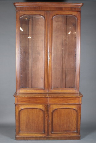 A Victorian mahogany bookcase with moulded cornice, fitted adjustable shelves enclosed by arched panelled doors, the base  fitted a double cupboard, raised on a platform base 47"w x 21"d  x 95"h