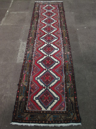 A contemporary Eastern red and white ground runner with 9  octagons to the centre 111" x 27"