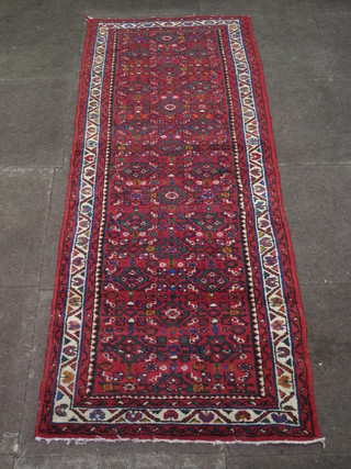 A red ground runner with all-over geometric design with  multi-row borders 76" x 28"