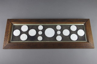 A rectangular oak frame containing 15 circular plaster intaglio plaques