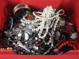 A red crate containing a collection of costume jewellery