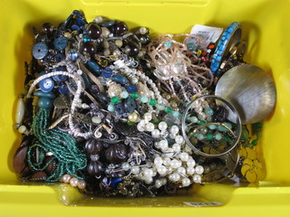 A yellow crate containing a collection of costume jewellery