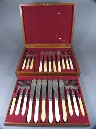 A set of 23 fish knives and forks comprising 12 forks - 1f, and  11 knives - 1 f, contained in a walnut canteen box