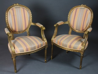 A pair of French style gilt painted open arm salon chairs, raised  on turned and fluted supports