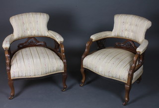 A pair of Victorian walnut tub back chairs upholstered in striped material, raised on cabriole supports