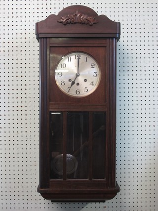 A chiming wall clock with silvered dial and Arabic numerals contained in an oak case