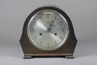 A striking mantel clock with silvered dial and Arabic numerals contained in an arch shaped oak case by Smiths