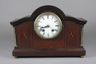 A 1920's striking mantel clock with enamelled dial and Roman  numerals contained in an arch shaped inlaid mahogany case