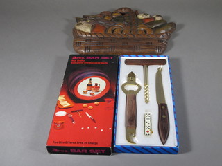 A 1960's bar set comprising bottle opener, corkscrew, a set of  dice and a cheese knife together with a carved wooden plaque in  the form of a basket of fruit 9"