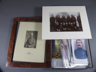 A portrait photograph of a WWI German soldier, a black and  white group photograph of various soldiers and a collection of  various military postcards