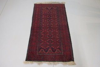 A red ground Belouche rug within multi-row borders 64" x 31"