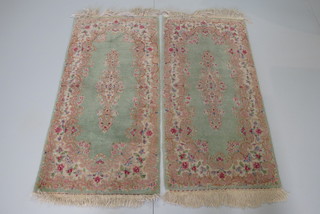 A pair of Persian green ground and floral patterned rugs 51" x 23"