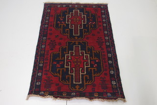 A Persian Balochi red ground rug with 2 octagons to the centre 56" x 35"