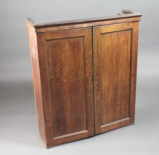 An 18th/19th Century oak hanging cabinet with moulded cornice,  fitted shelves enclosed by a panelled door 32"w x 10"d x 37"h